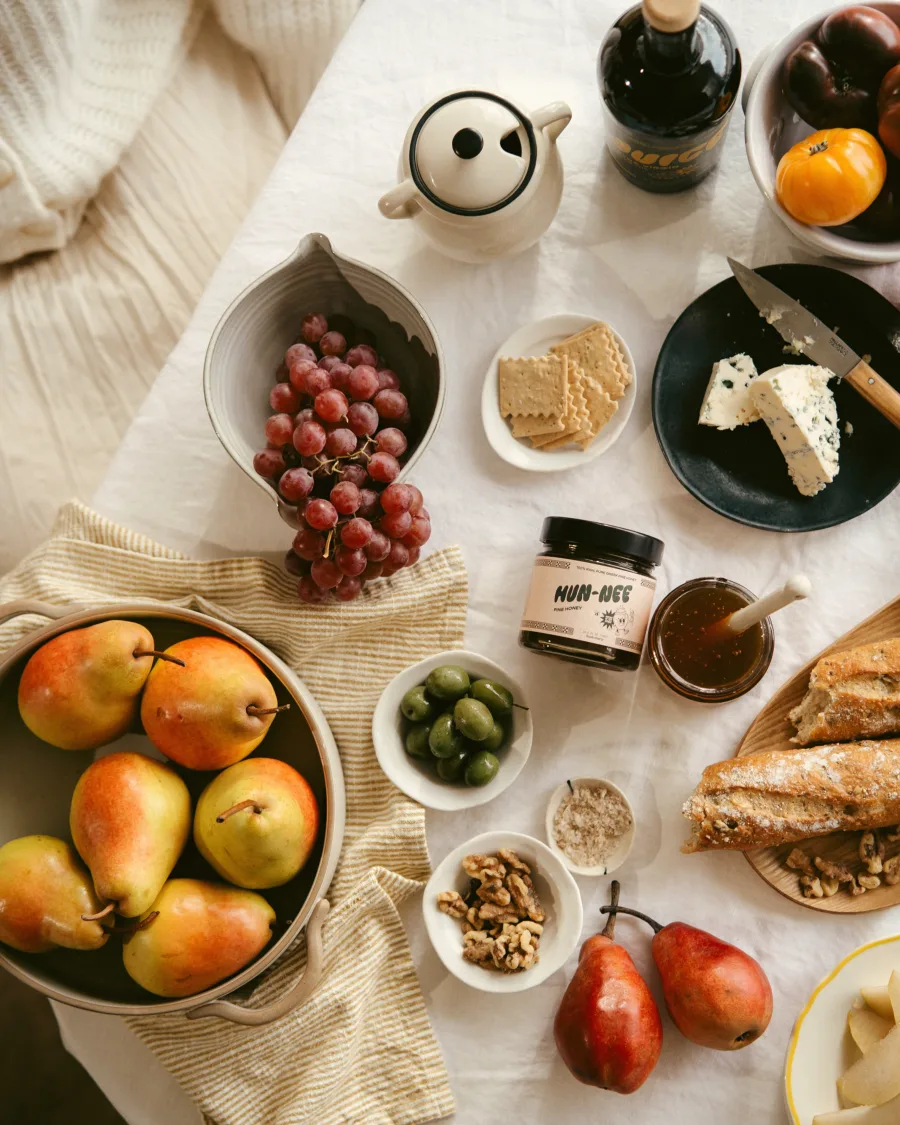 A jar of Hun-nee pine honey with bread, olives, and cheese.