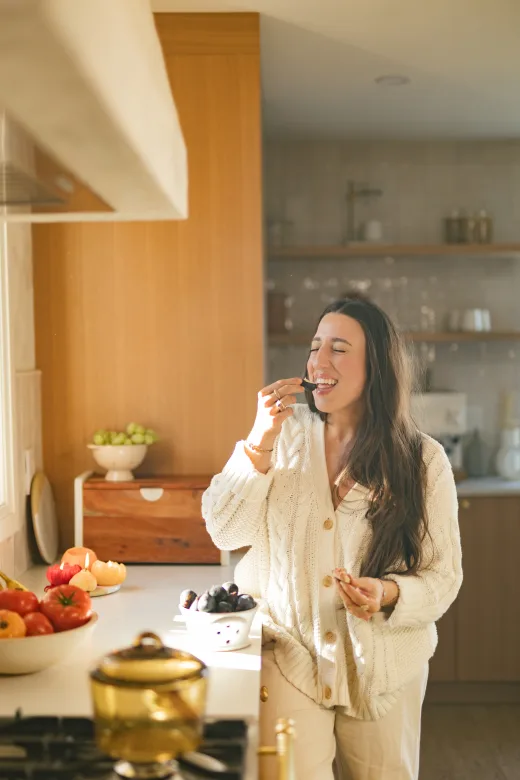 Maria standing in a kitchen and holding a drink.