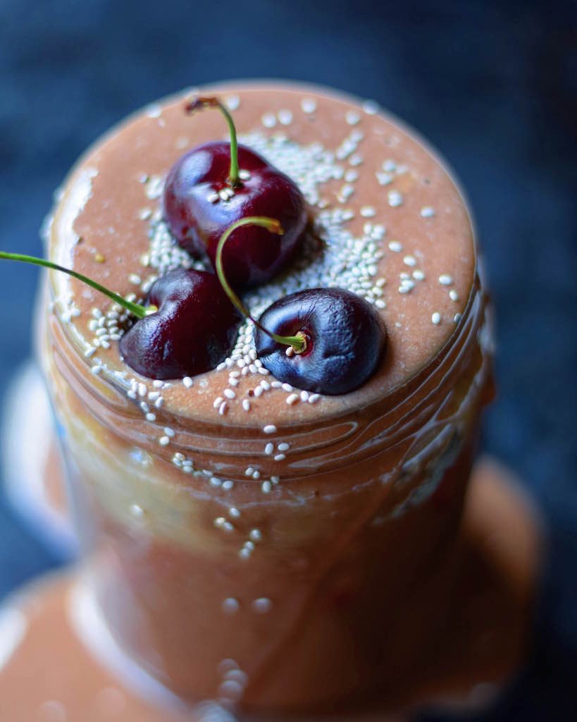 Close up of an Arbonne protein shake with cherries on top.