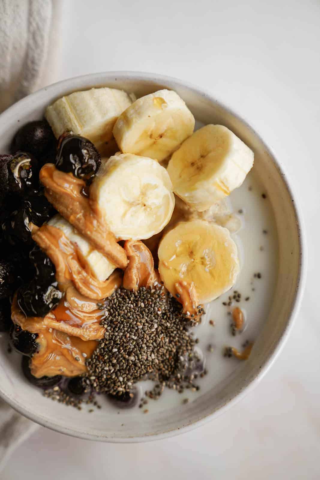 low gi breakfast in a bowl with fruit, peanut butter, and chia seeds on top.