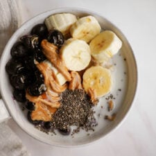 low gi breakfast in a bowl with fruit, peanut butter, and chia seeds on top.