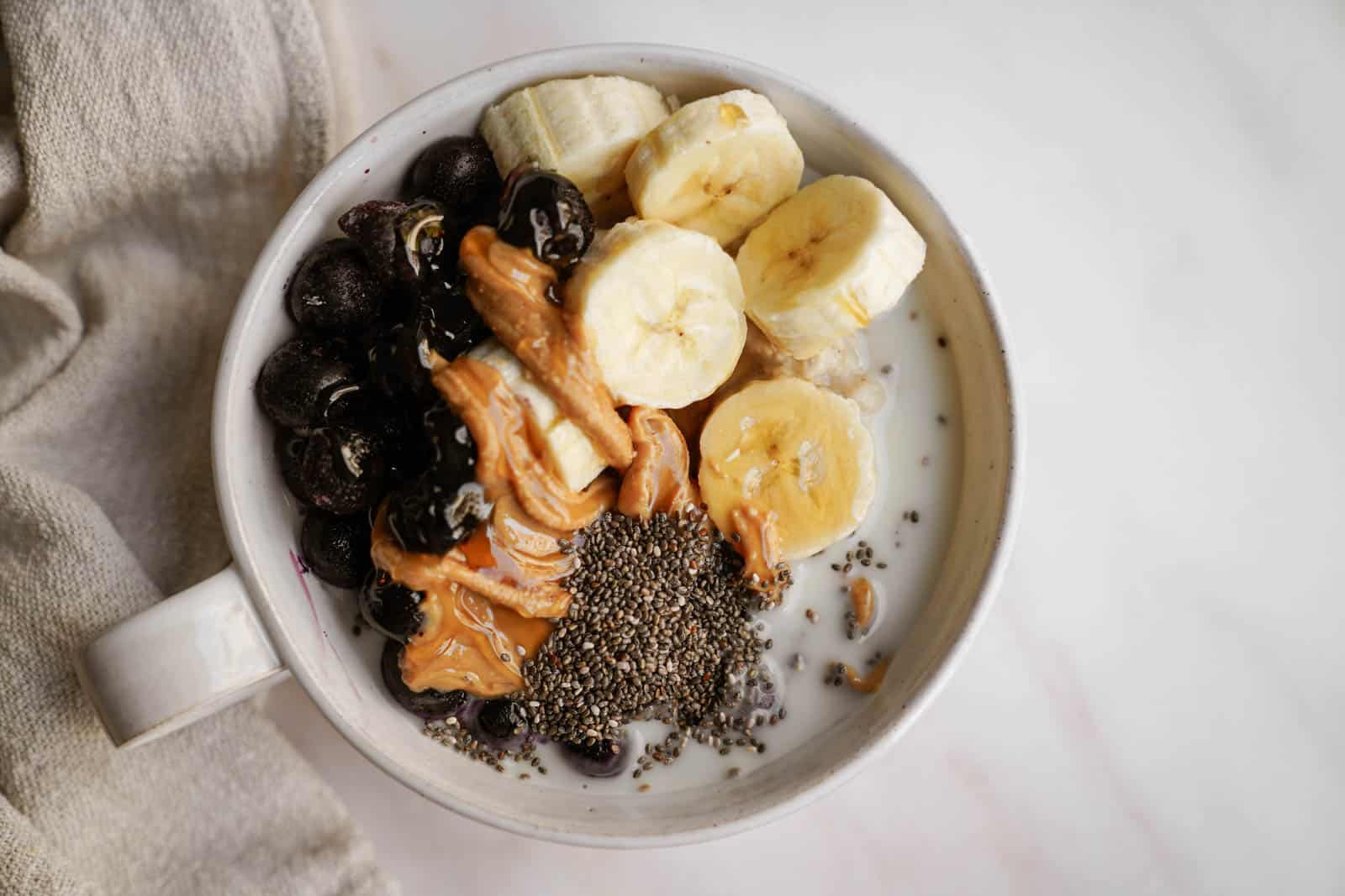 low gi breakfast in a bowl with fruit, peanut butter, and chia seeds on top.