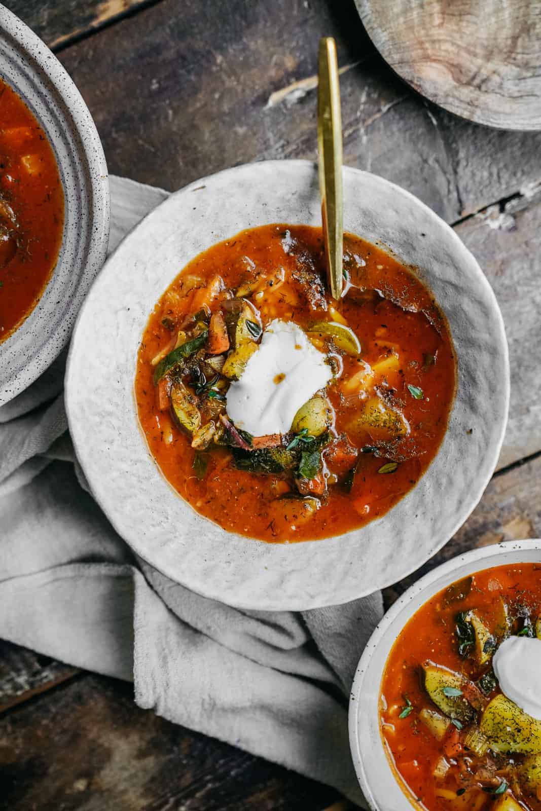 Bowls of vegetable orzo soup on wood table.