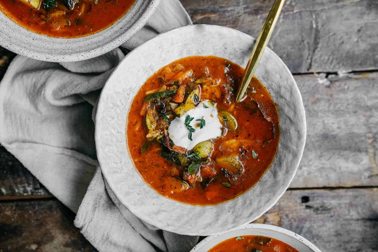 Bowls of vegetable orzo soup on wood table.