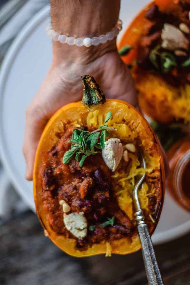 spaghetti squash vegan recipe with hand holding squash with a fork in it