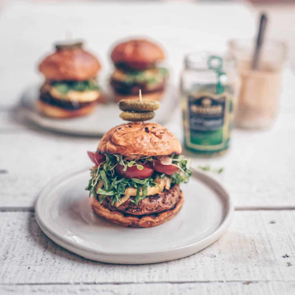 A gorgeous stacked burger with vegan big mac sauce on it.