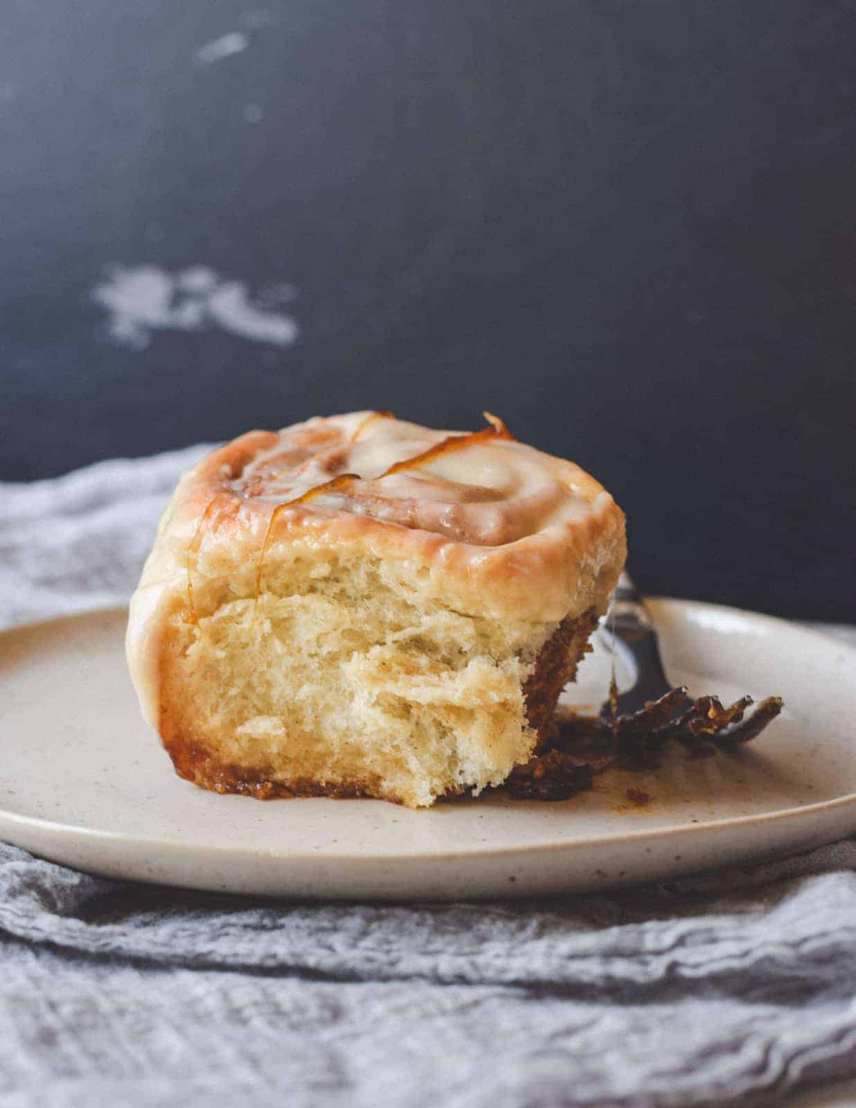 One sticky cinnamon rolls on a plate with a fork