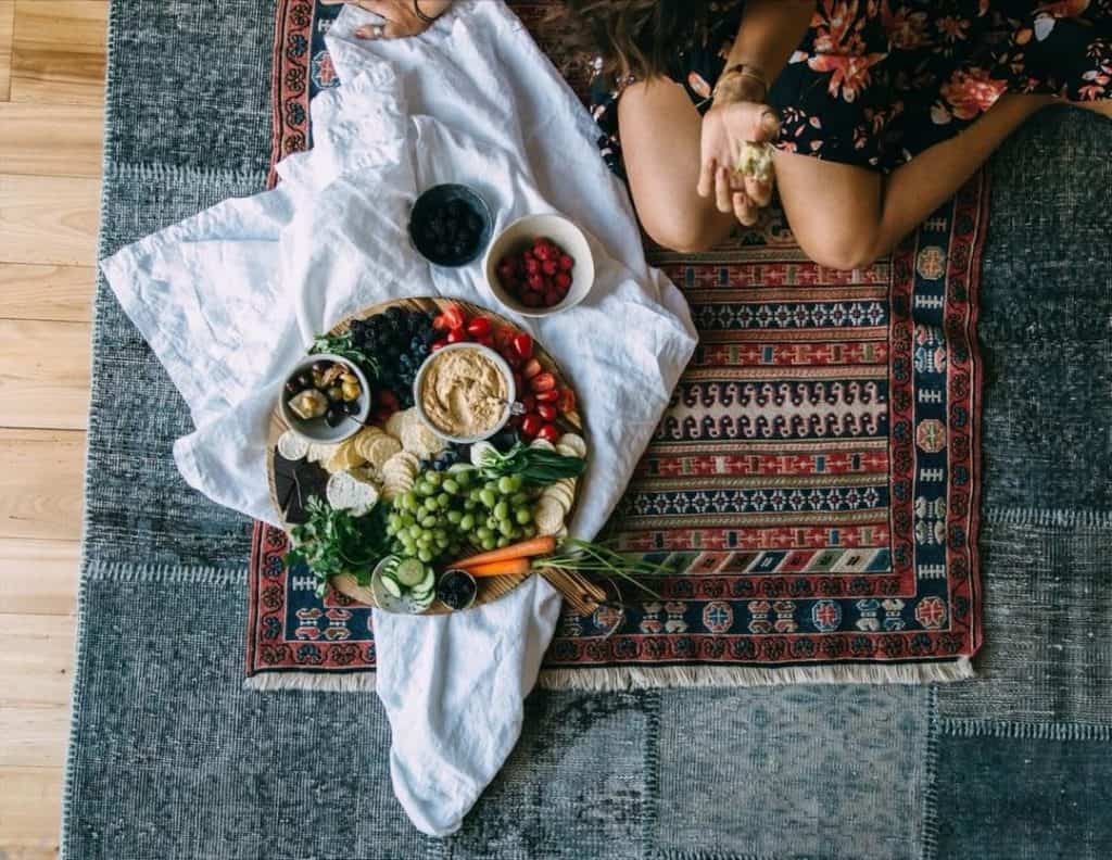 Overhead shot of Maria on carpet with big spread of veggies and lentil hummus.