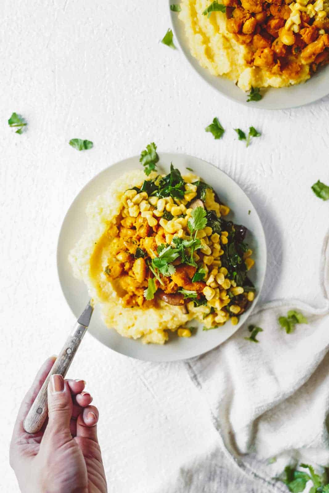 Vegan grits with collard greens in a serving dish on a white table.