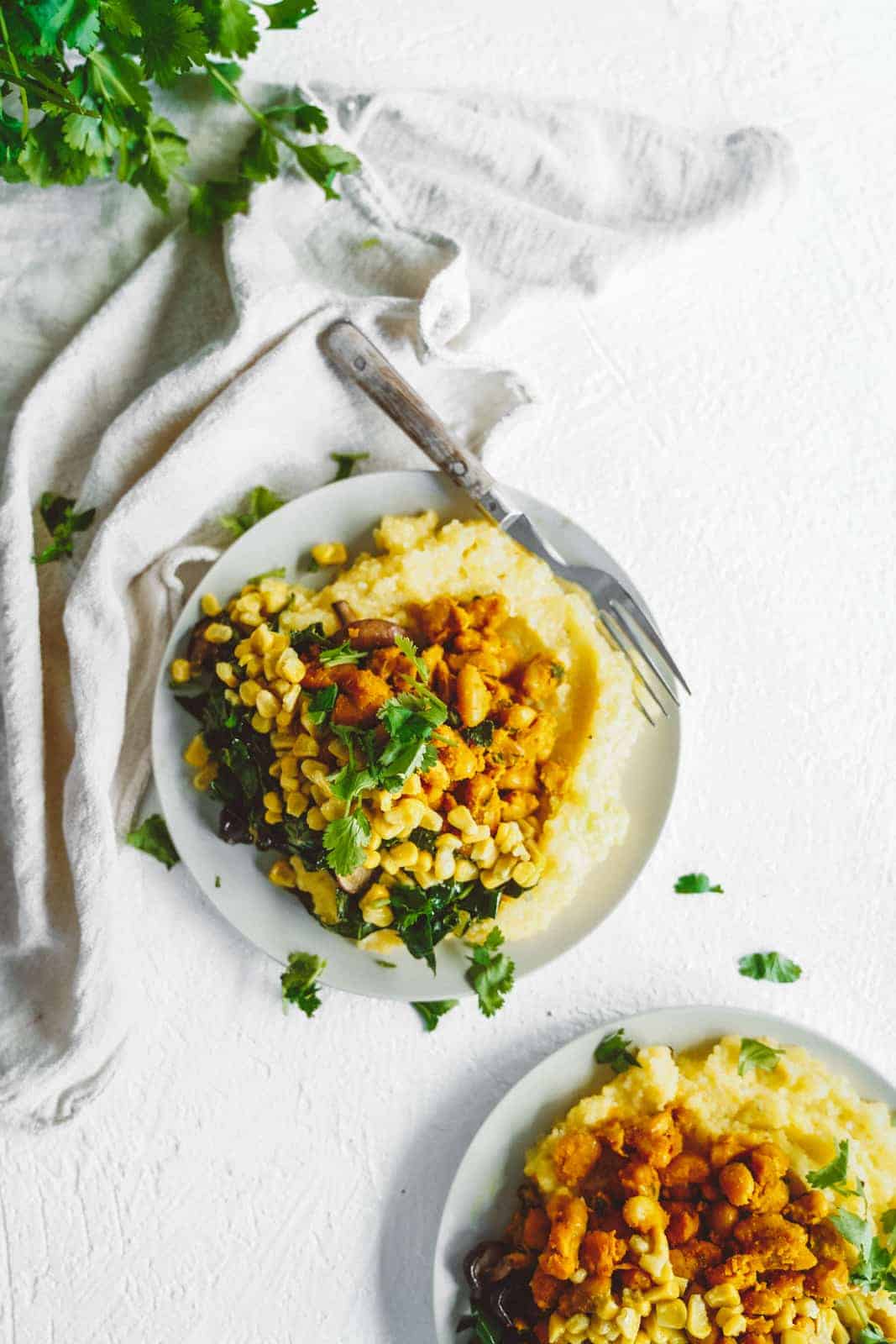 Vegan grits with collard greens in a serving dish on a white table.