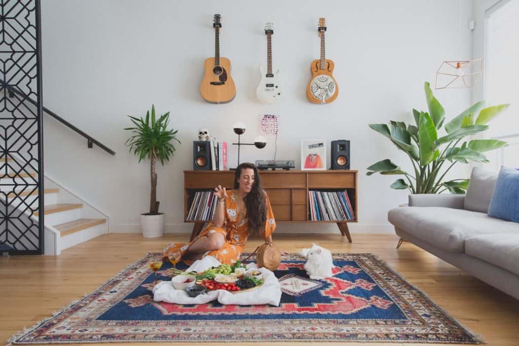 Maria sitting on floor with a vegetable tray with lentil hummus.