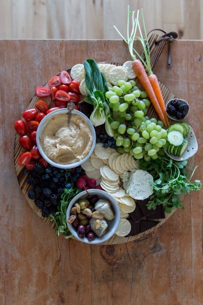Overhead shot of a colorful charcuterie board loaded with veggies and lentil hummus