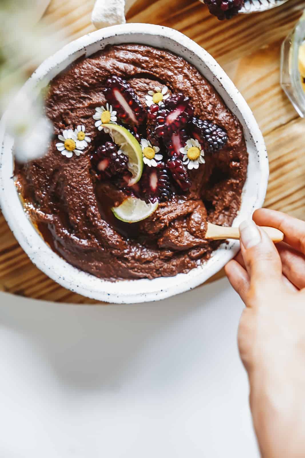 Chickpea dessert in a bowl with fresh flowers and fruit on top.