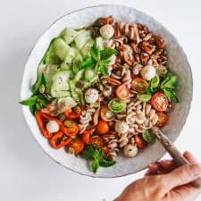 Easy Pumpkin Seed Pasta Salad in a bowl on a counter with a spoon serving it.