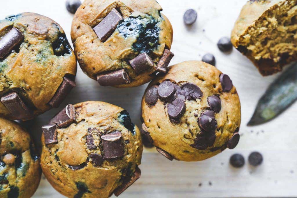 A bunch of vegan chocolate chip muffins with large chocolate chunks in them.