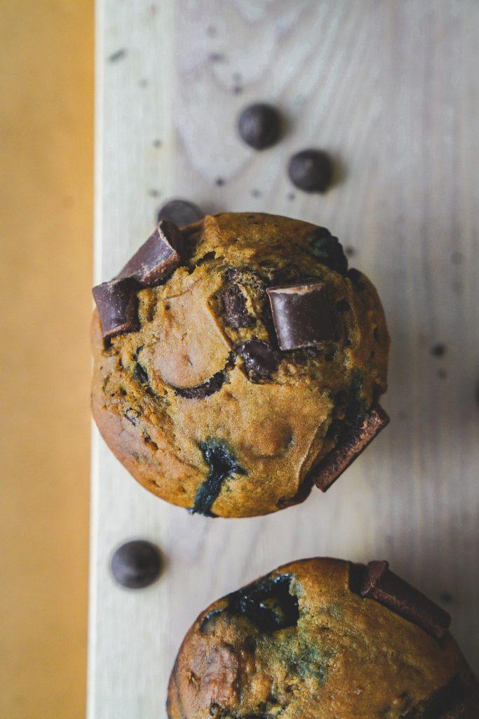 Top shot of a vegan chocolate chip muffin with blueberries with large chunks of chocolate on top.