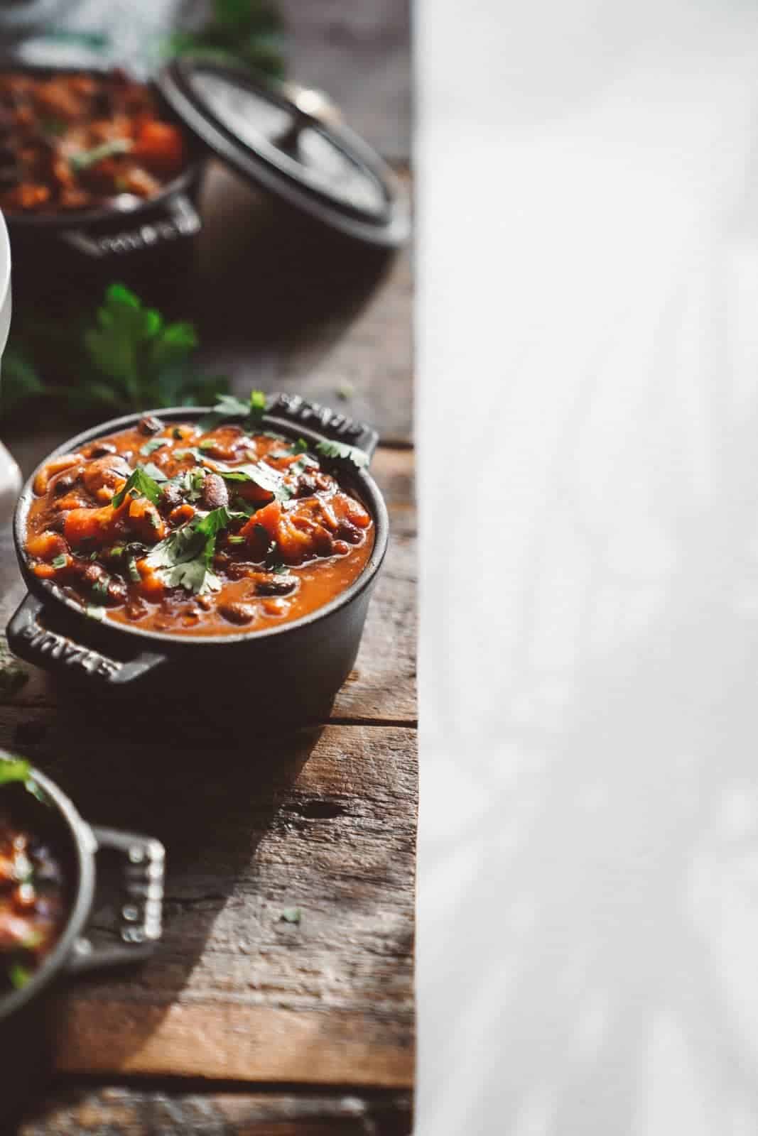 Big bowl of chili on the side of a wood table. One of the best recipes to make in September.