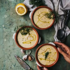 bowls of plantbased soup on counter with hands reaching in for bowl