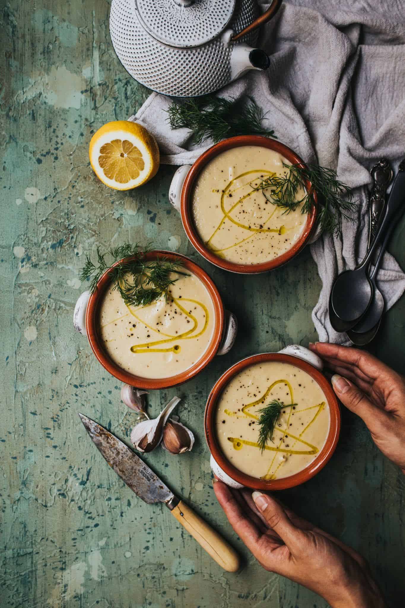 bowls of plantbased soup on counter with hands reaching in for bowl