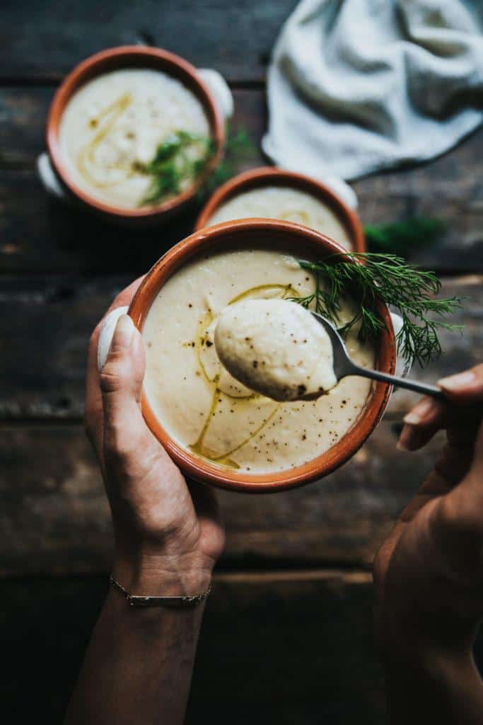 Bowl of plantbased soup with someone taking a spoonful out of it.