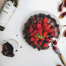 Delicious bundt cake sitting on white table with beautiful red fresh raspberries to decorate the top.