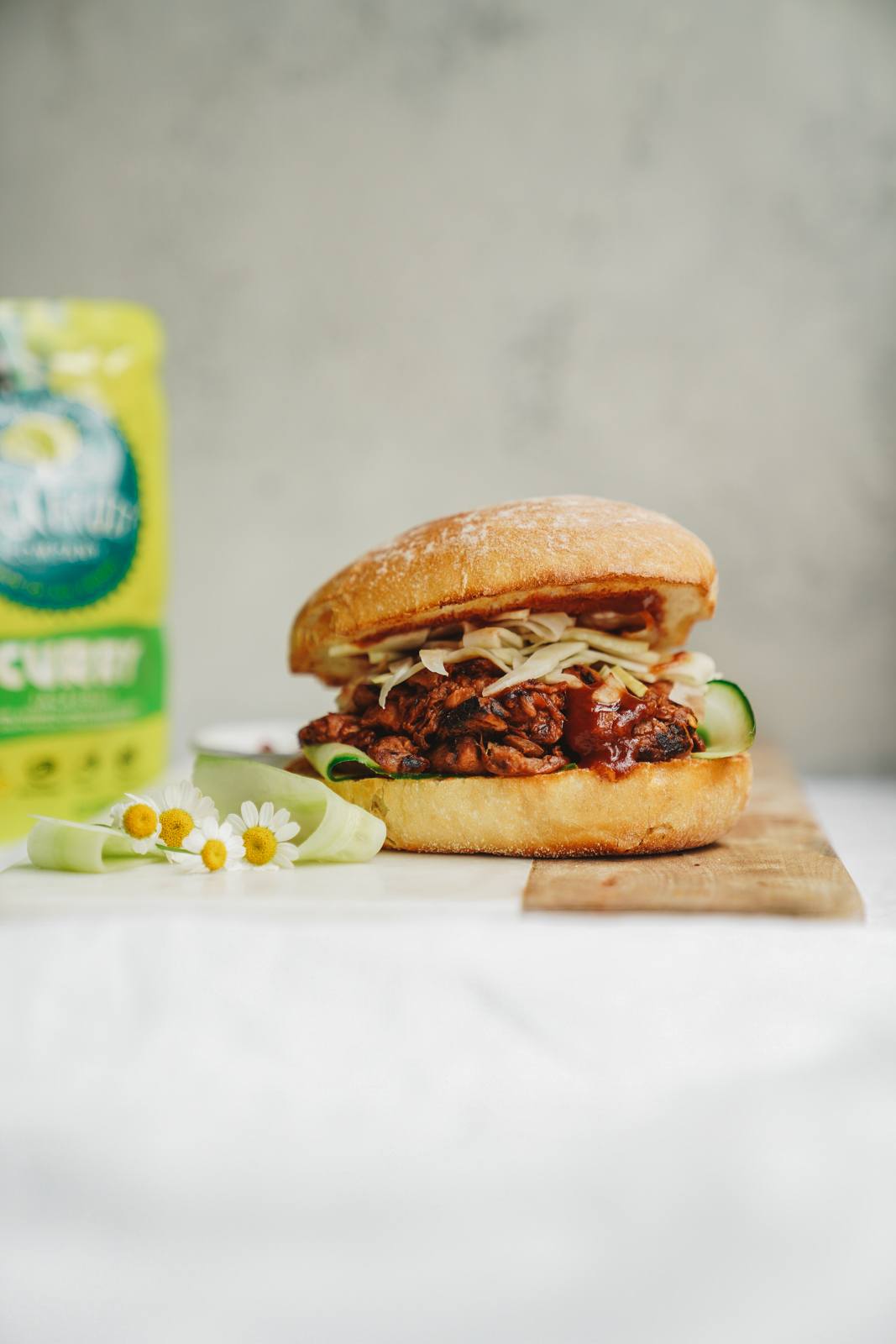 Beautifully stacked jackfruit burger patty recipe on cutting board with bag of jackfruit in the background.