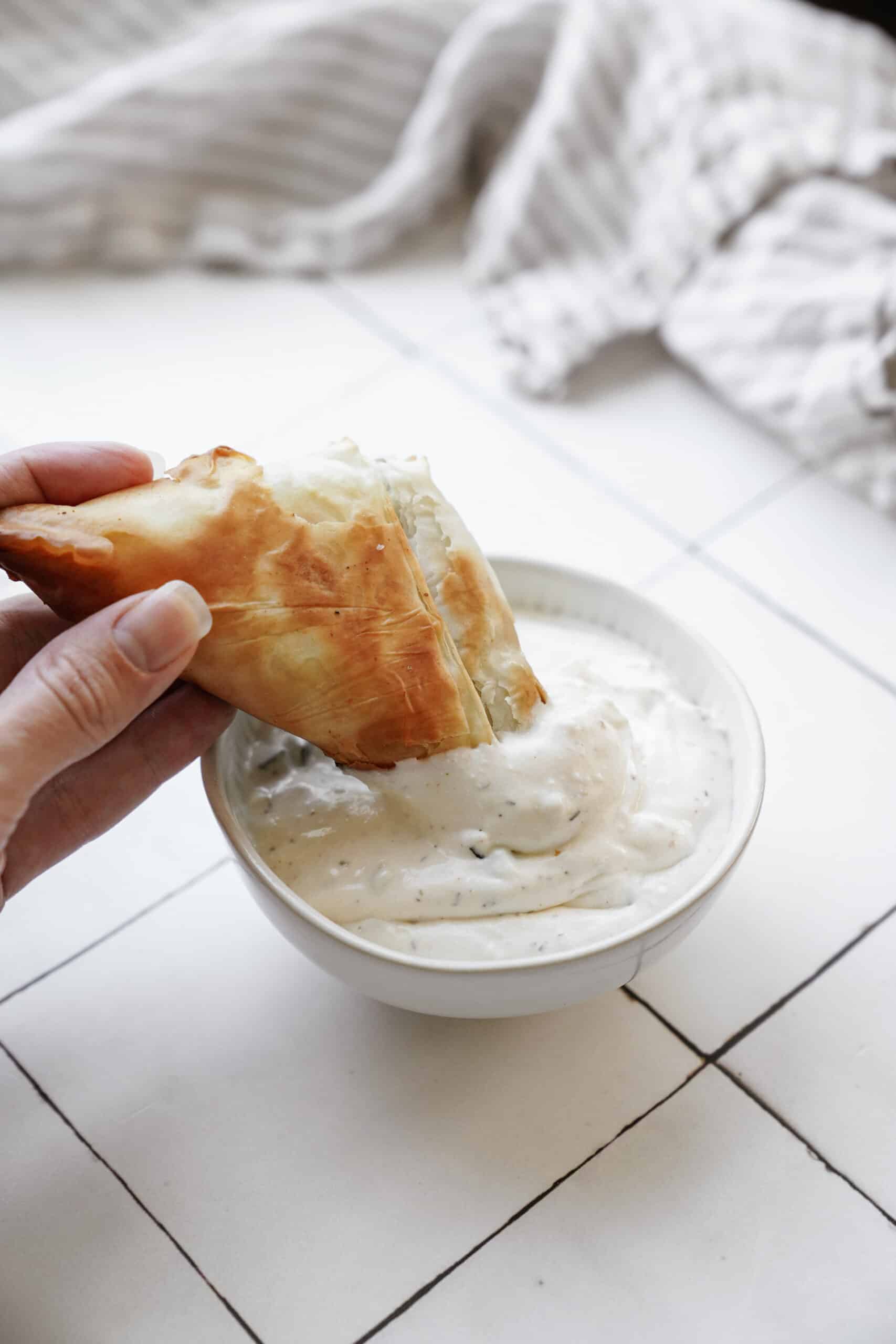Dipping spinach pie into tzatziki sauce