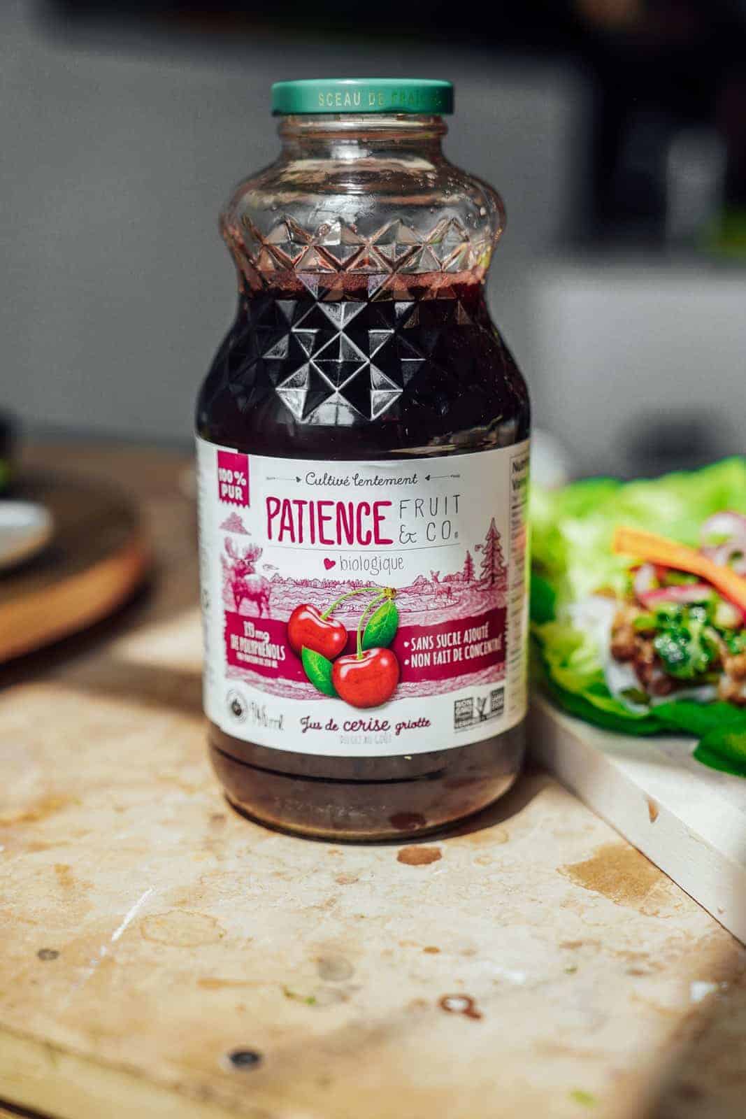 Bottle of Patience Fruit & Co. Cherry Juice sitting on countertop with lettuce wraps in the background.