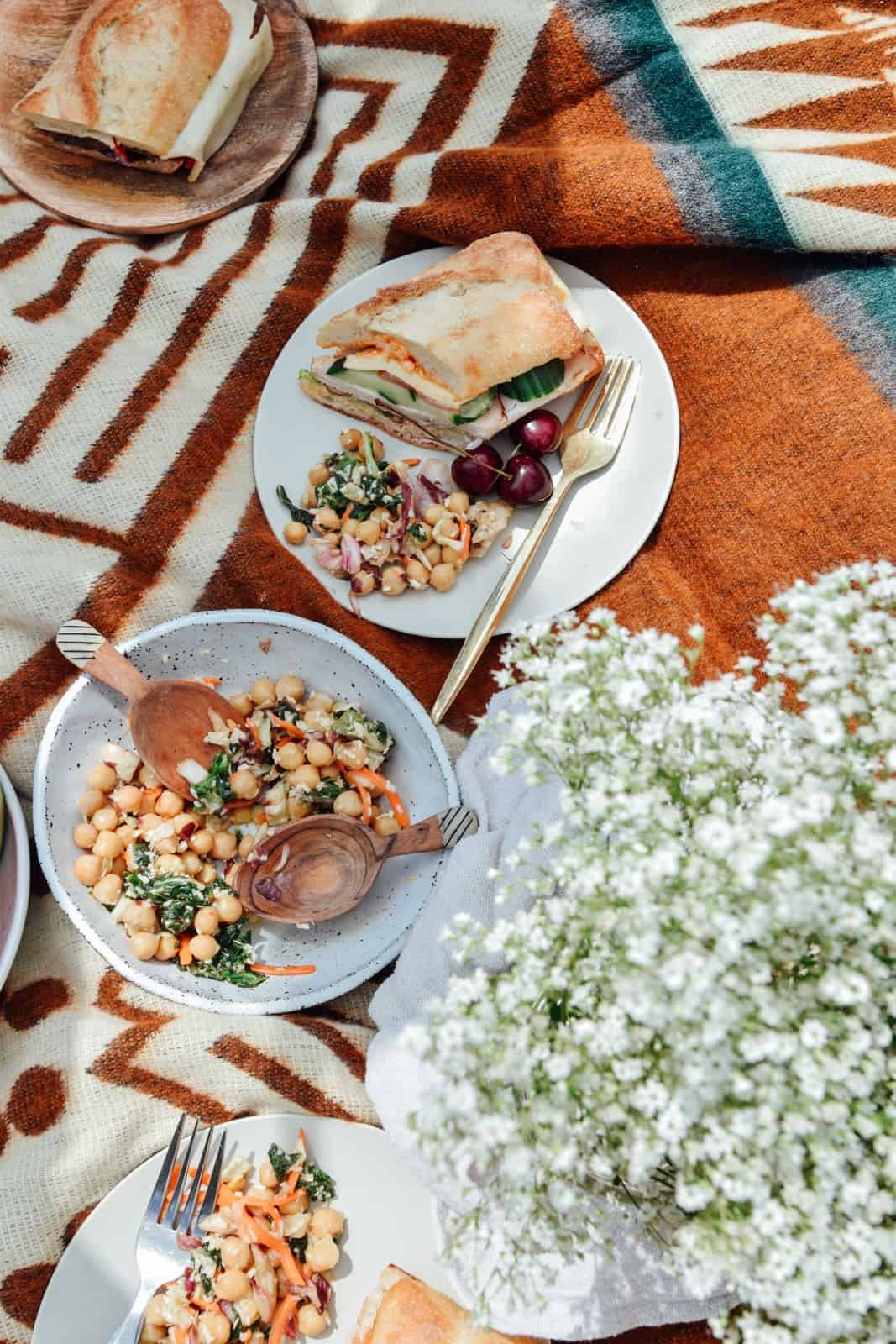 A Sandwich and salad picnic on a blanket.