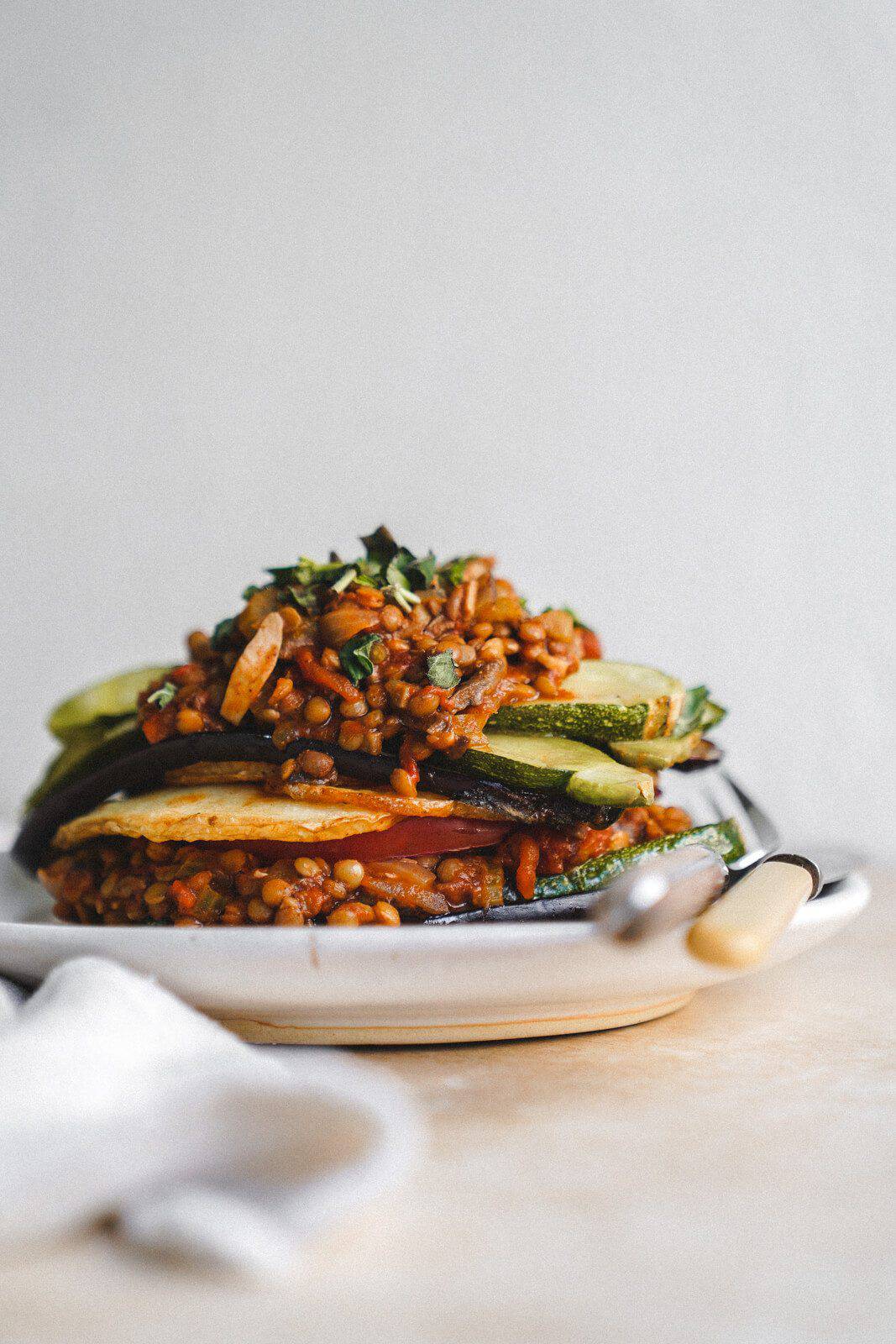 A summer spin on Moussaka. Photo of moussaka taken from the side on a white serving plate.