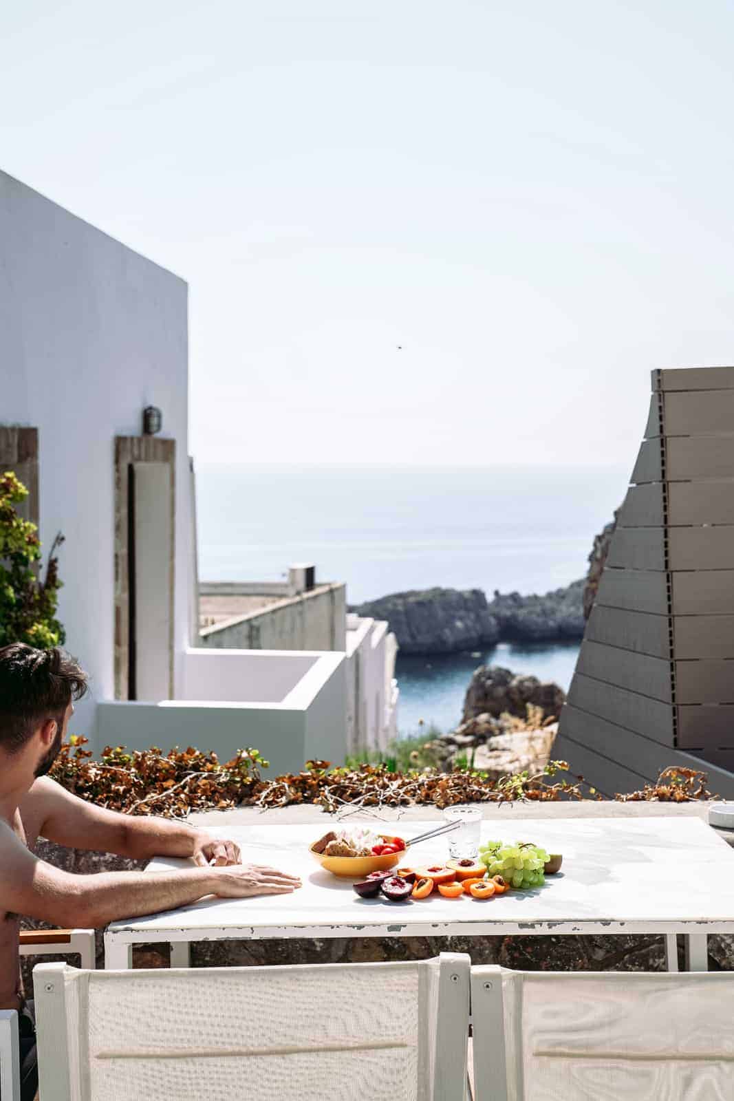 Guy sitting at table with food overlooking Mykonos, Greece.