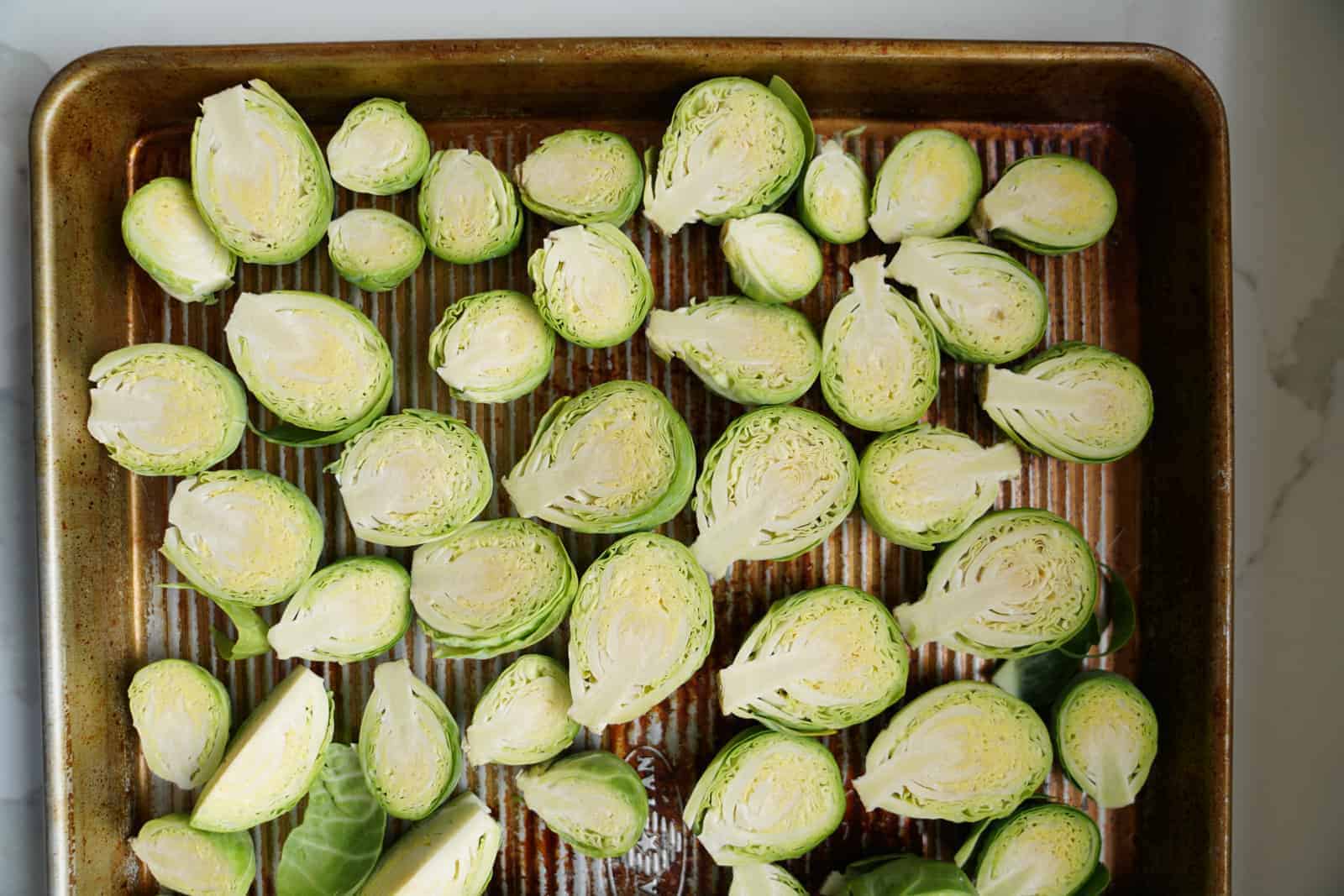 Raw brussel sprouts laying on pan ready to bake.