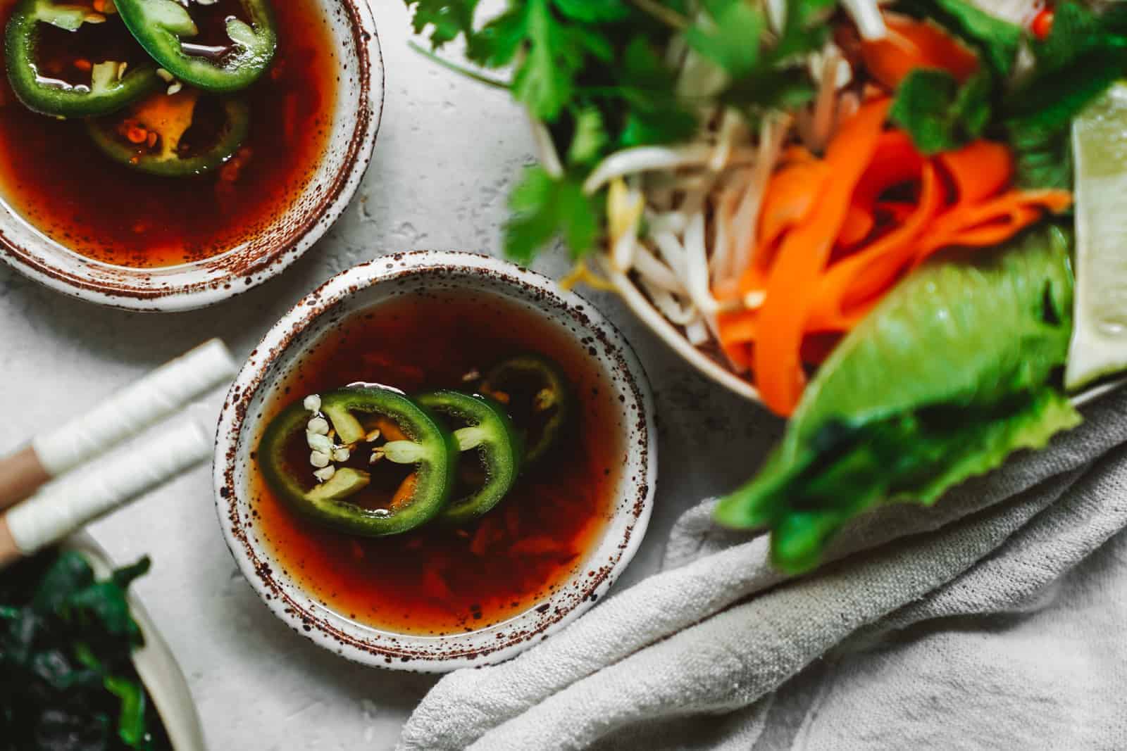 Vegan fish sauce substitute in little bowls with fresh peppers on top