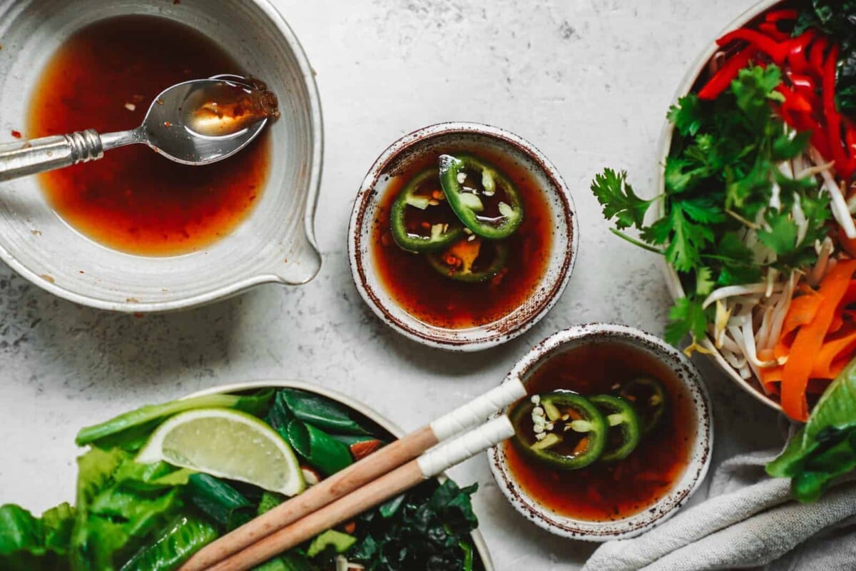 Little bowls of Vegan Fish Sauce substitute next to ingredients for the spring roll bowl.