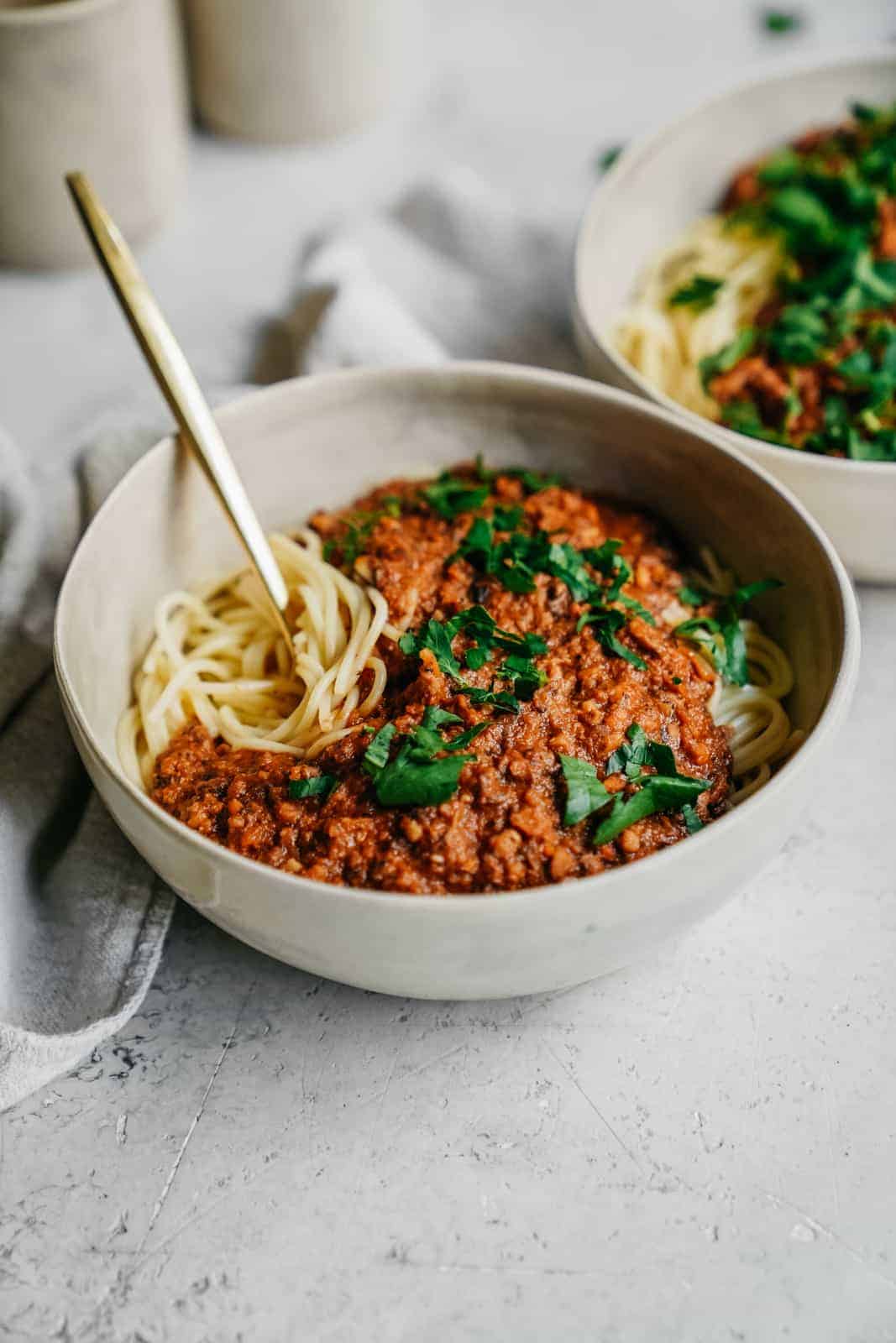 Yummy bowl of hot spaghetti with vegan meat sauce on top with a napkin and ready to eat.