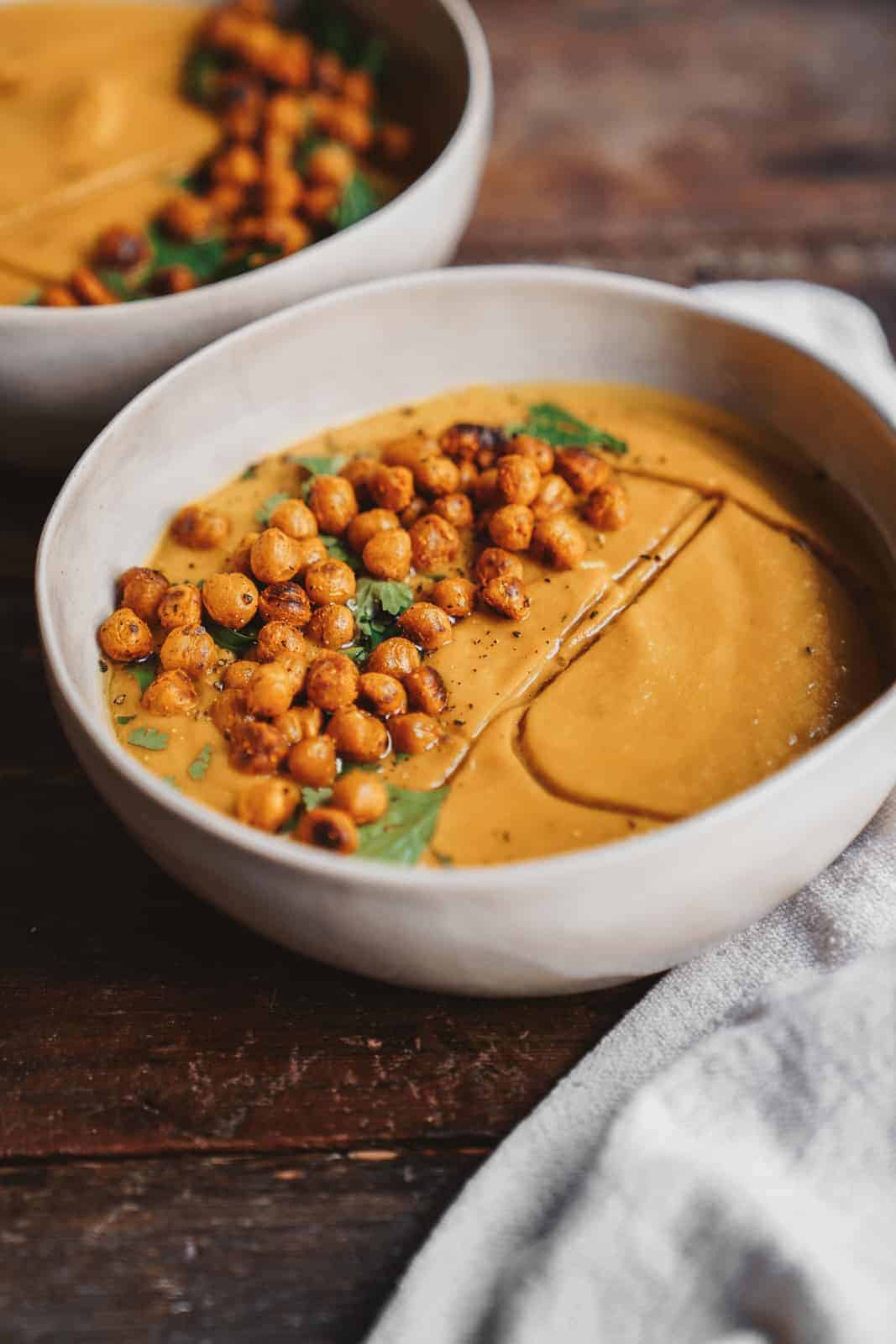 Big creamy bowl of Vegan Vegetable Soup sitting on wood countertop.