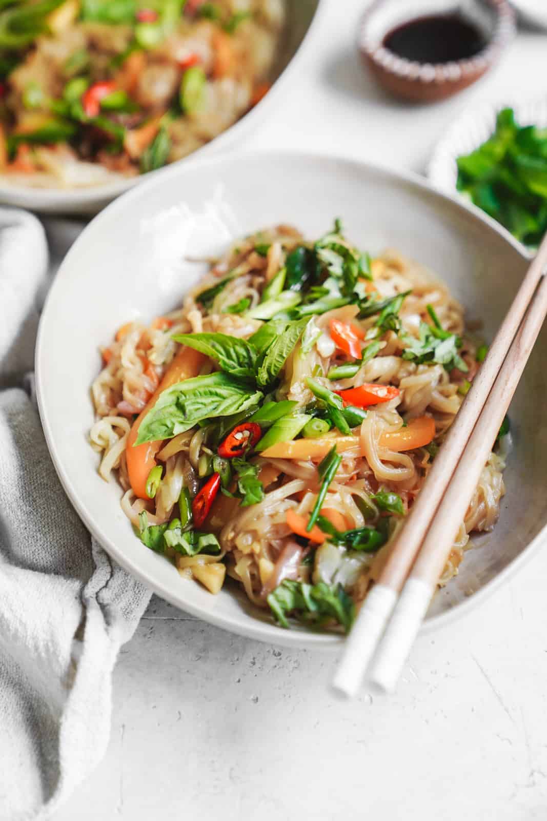 White bowl filled with this drunken noodles recipe with chopsticks.