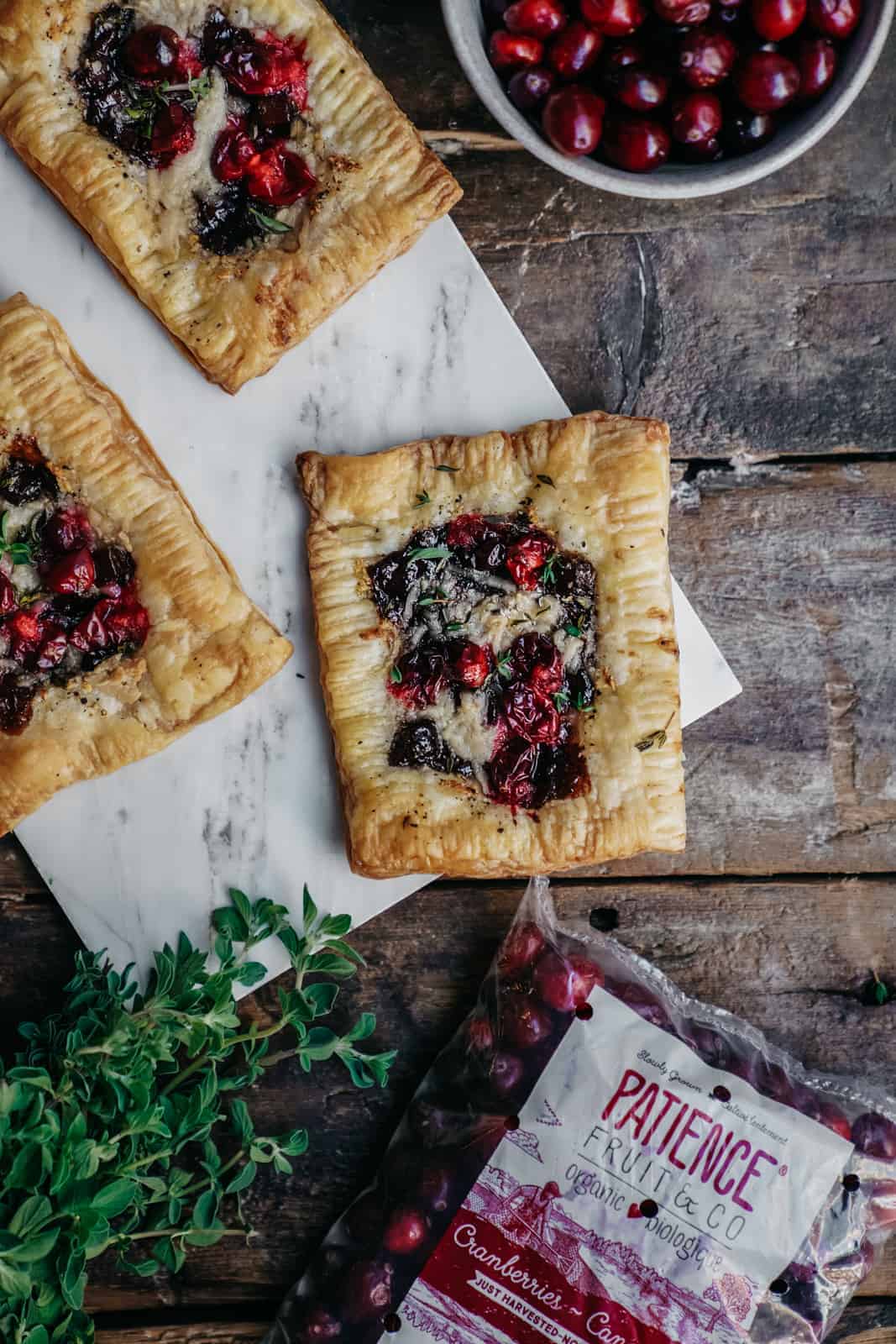 vegan cranberry cheese tarts on cutting board surrounded by fresh cranberries.