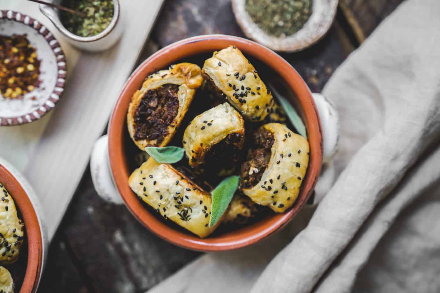 Bowl of vegan sausage rolls surrounded by spices.