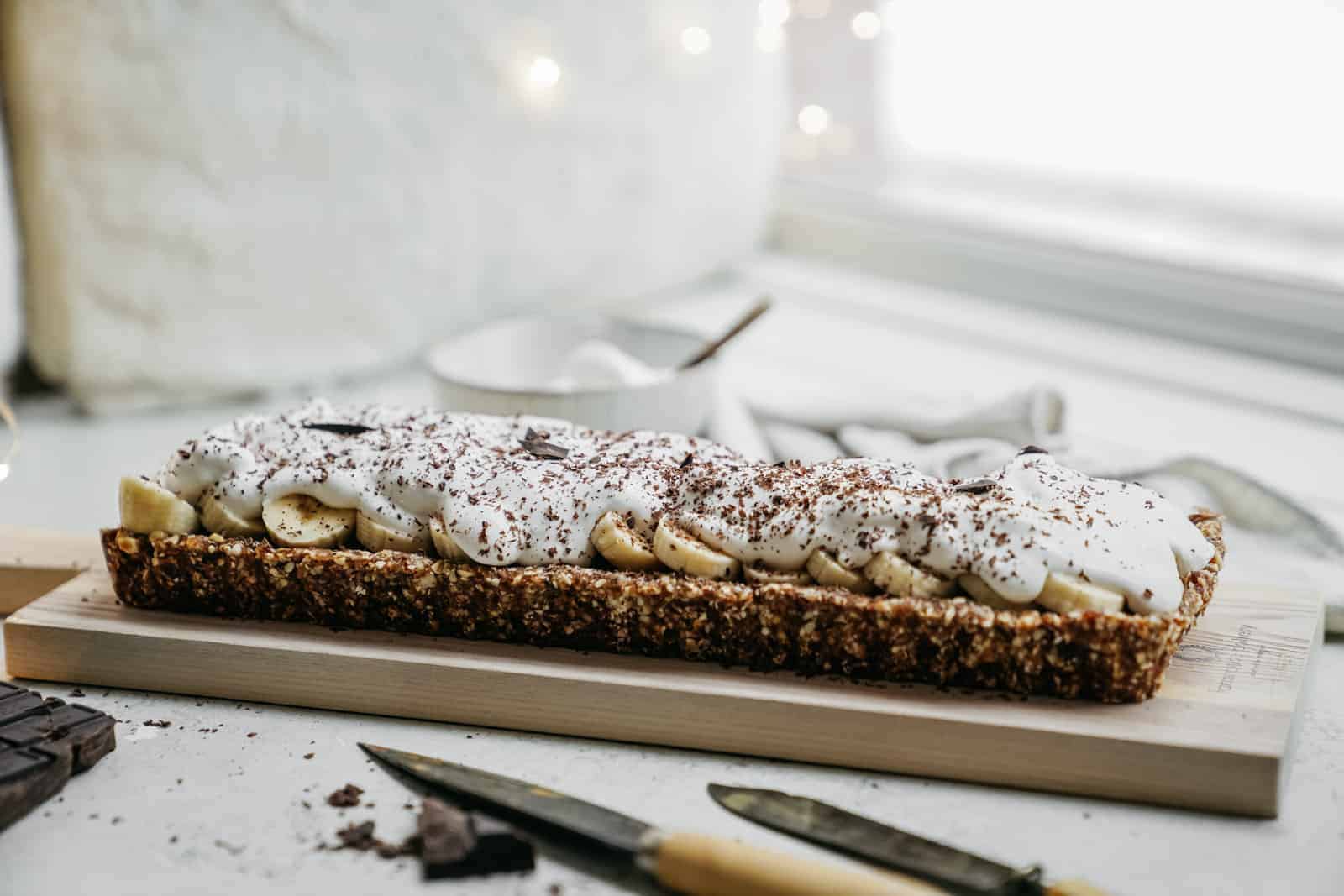 Side angle of a perfect vegan banoffee pie recipe on cutting board.