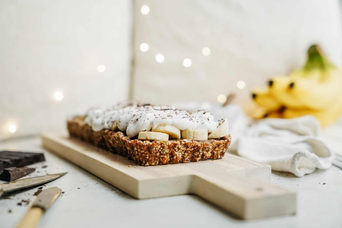 vegan banoffee pie on cutting board with fresh bananas