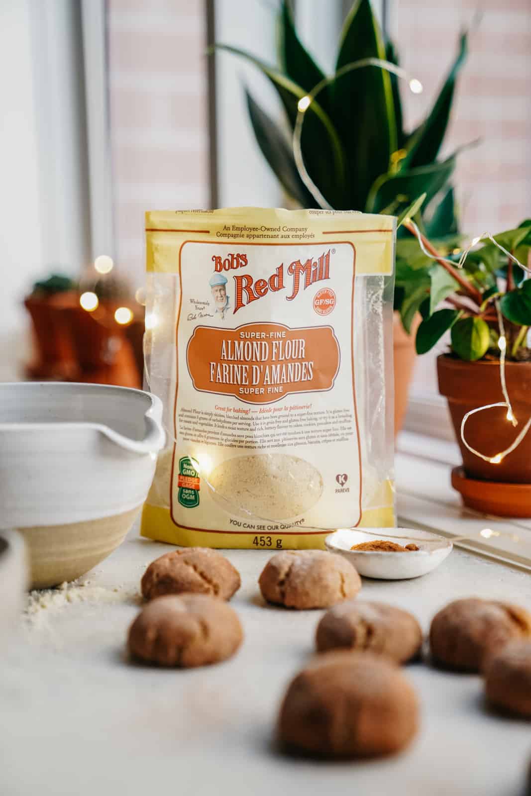 Bag of Bob's Red Mill Almond Flour with cinnamon sugar cookies scattered in front of bag on table.