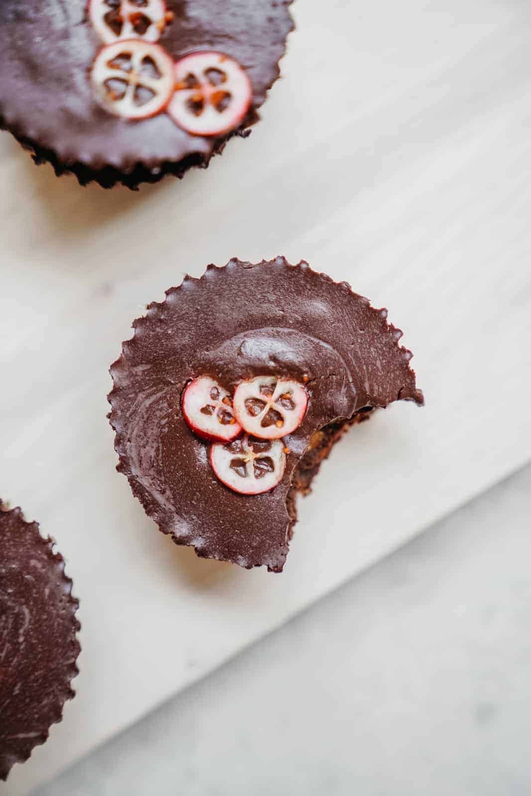 Yummy Hazelnut Caramel Chocolate Cups with a bite out of it sitting on white counter. A go-to quick vegan meal idea.