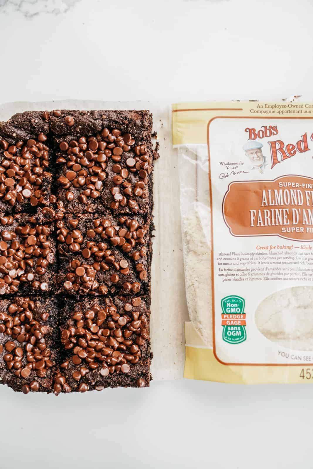 Batch of Almond Flour Brownies sitting on counter next to a bag of Almond Flour.