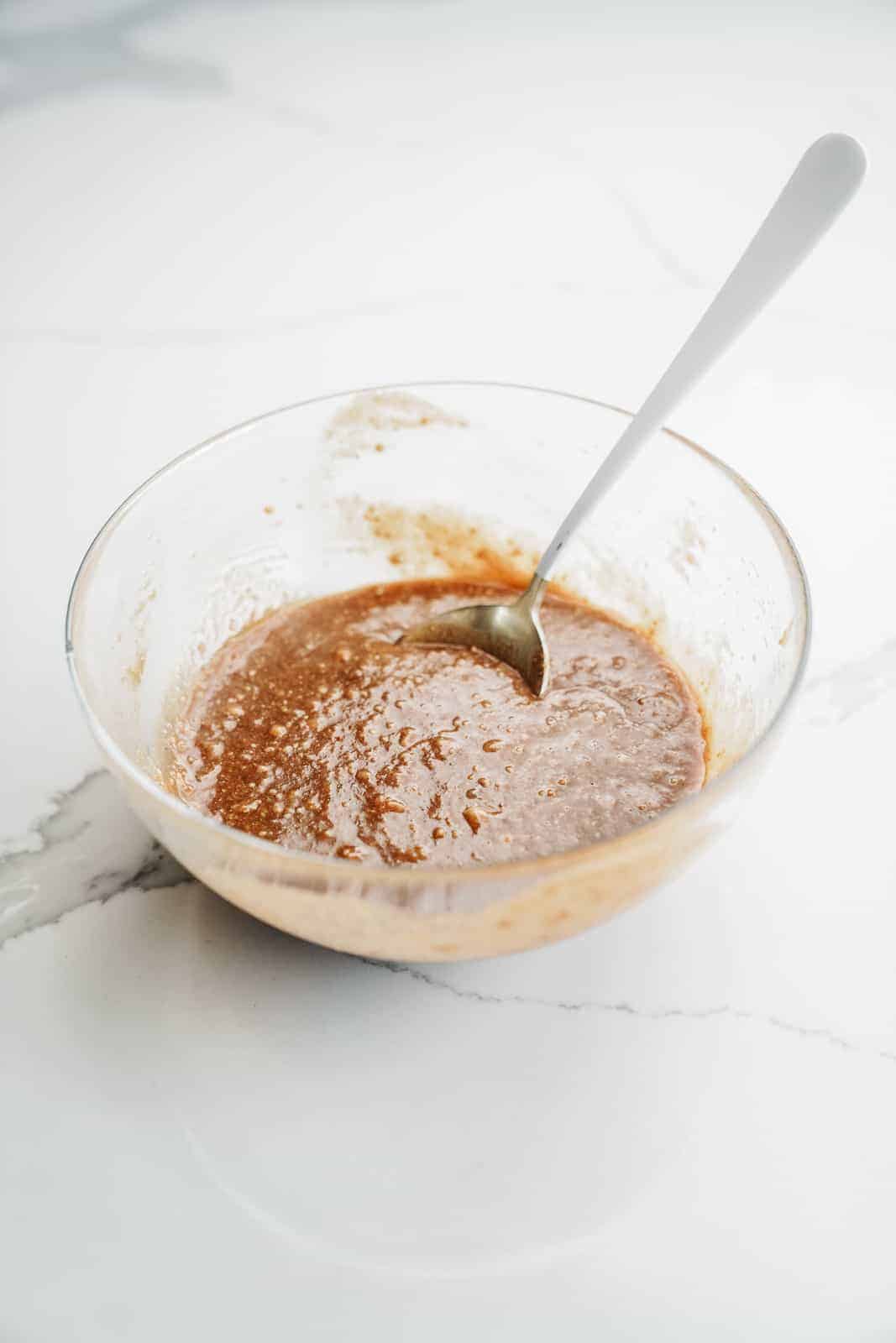 Wet ingredients mixed in a glass bowl on the counter.