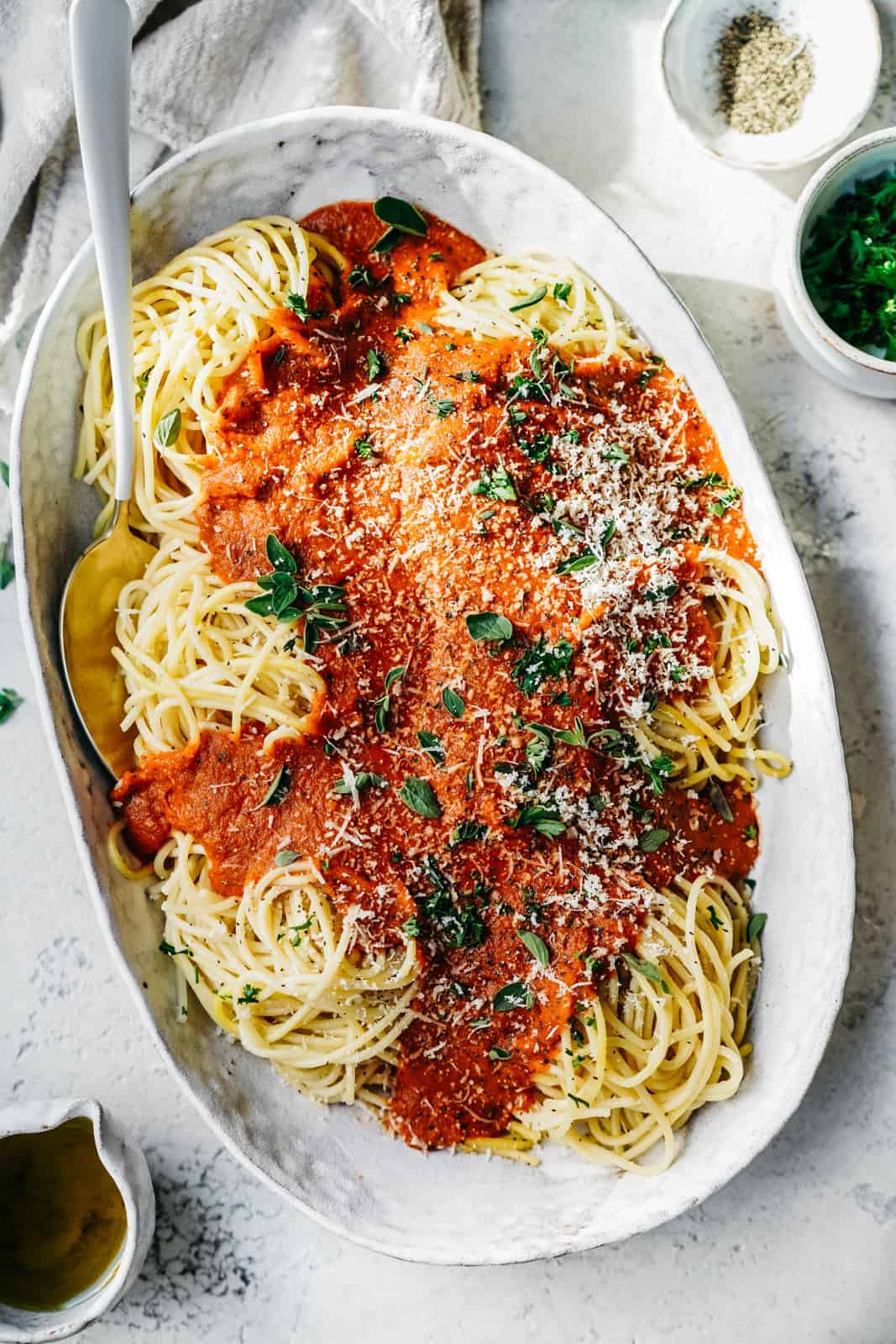 Big serving dish of Spaghetti with Vegan Pasta Sauce and vegan parmesan cheese sprinkled on top.