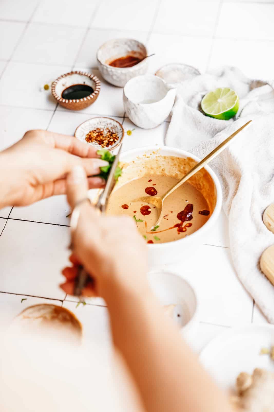 Hands chopping garnish into a bowl of soup.