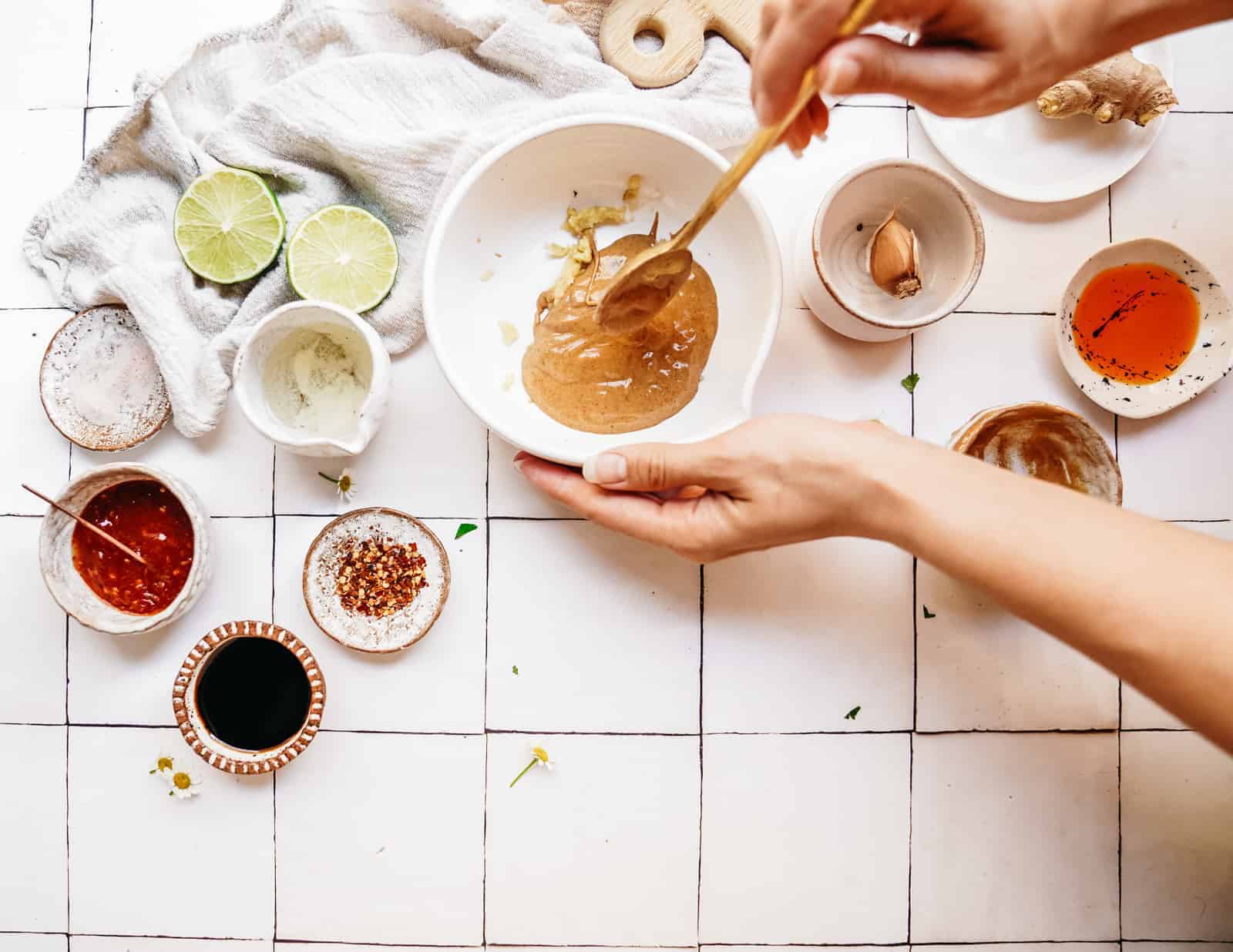 Person showing you how to make peanut sauce in a bowl on a white countertop