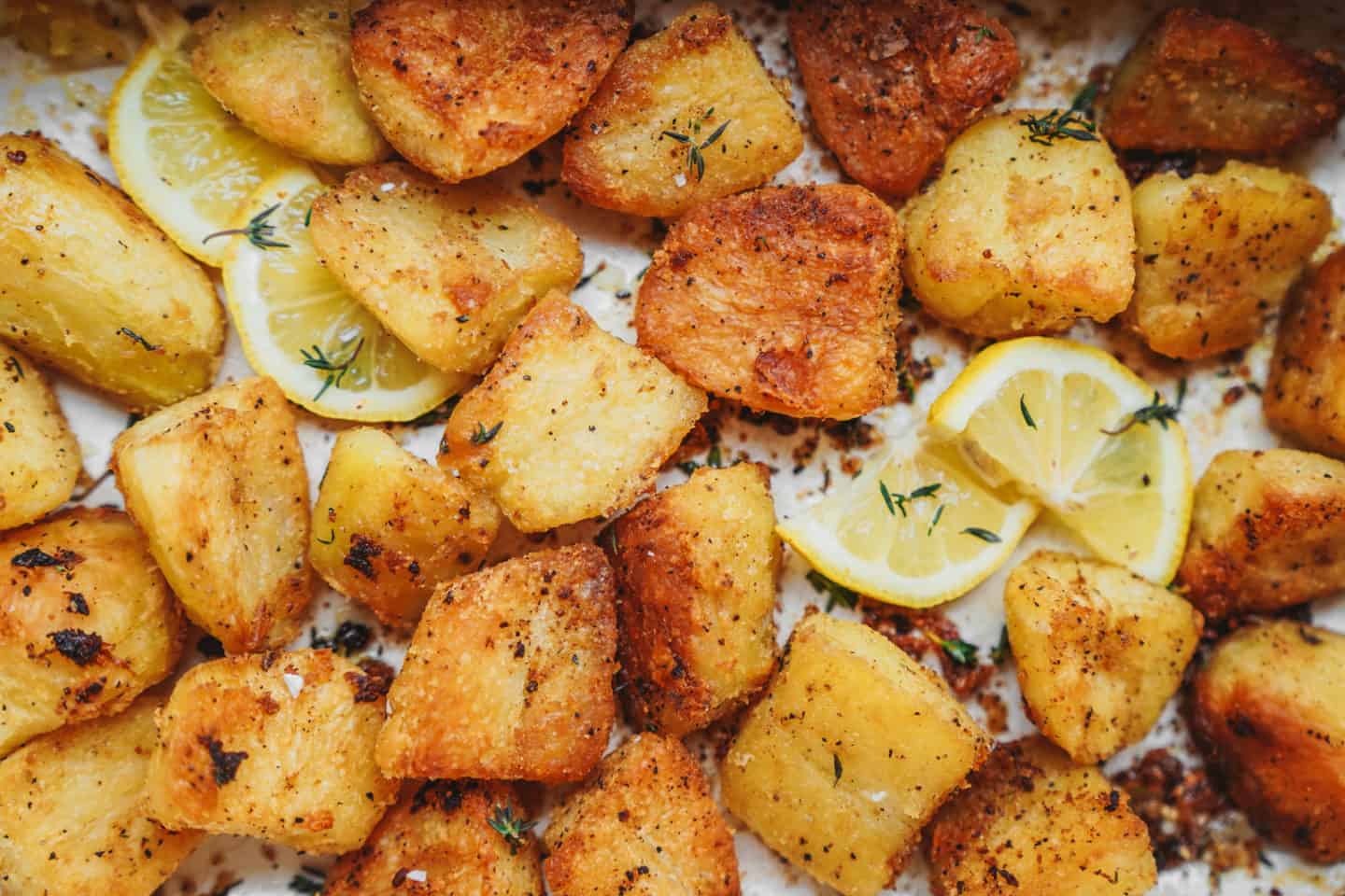 Crispy roasted potatoes on a baking sheet with lemon