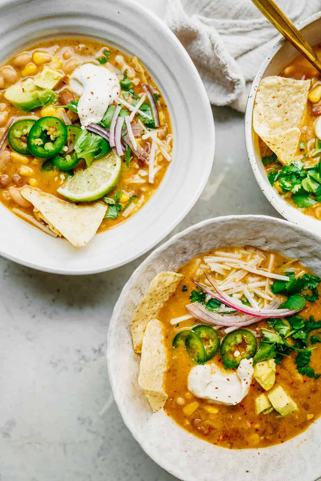 Big bowl of Vegan White Bean Chili sitting on table loaded with all the fixings.
